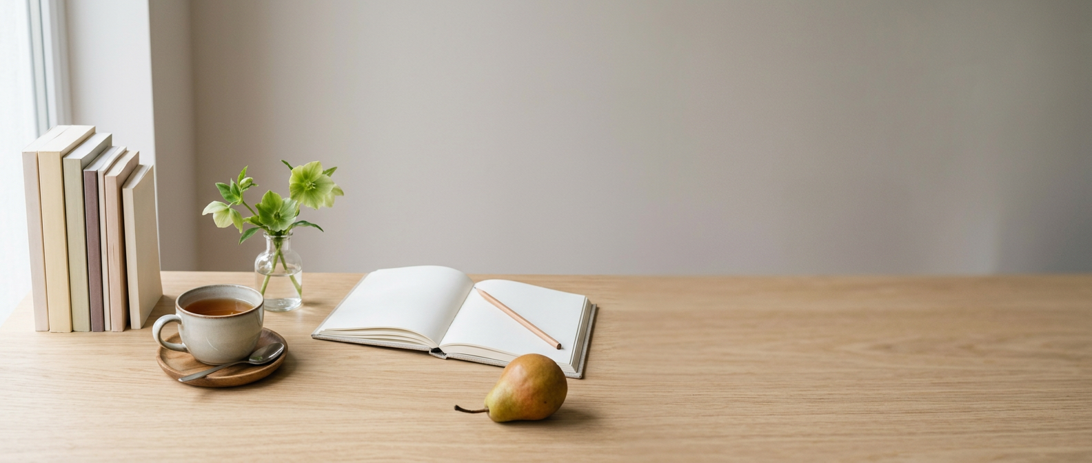 Une table en bois clair avec une pile de livres, un carnet ouvert, une tasse de thé et une poire. Image générée.